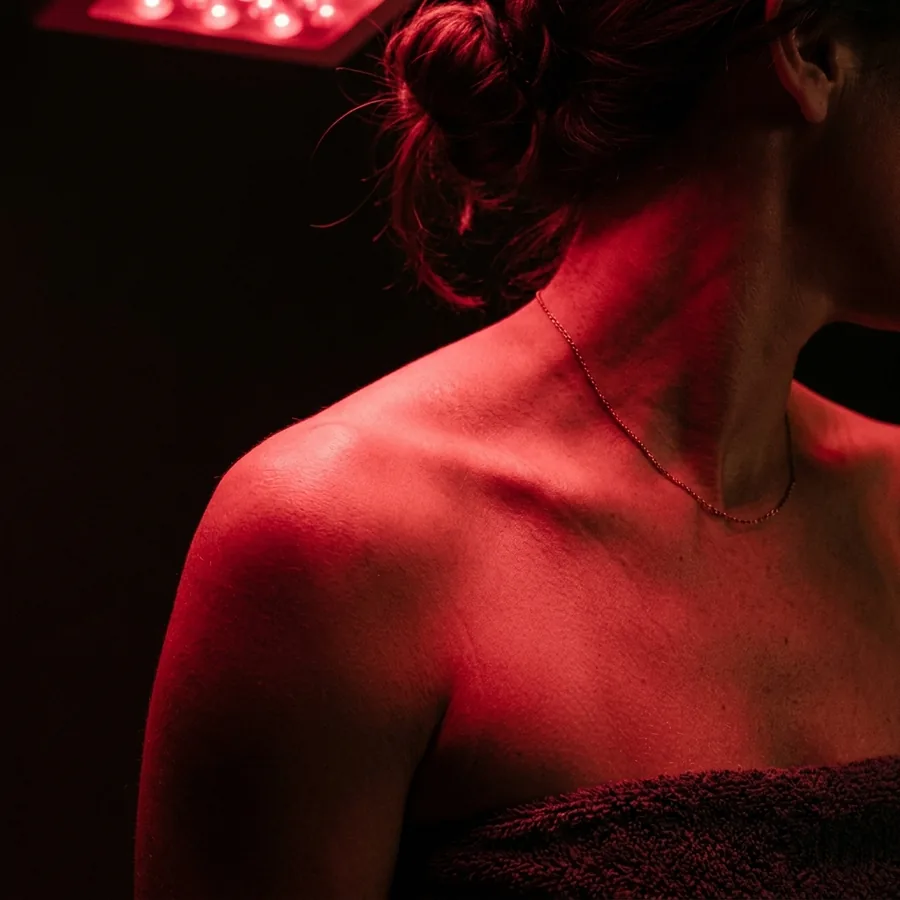 Red therapy light washing over a shoulder